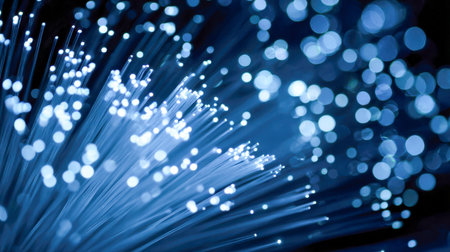 Vibrant blue fiber strands shimmer with luminous dots, set against a glittering, out-of-focus backdrop that symbolizes fast data flow and cutting-edge digital networks.の写真素材