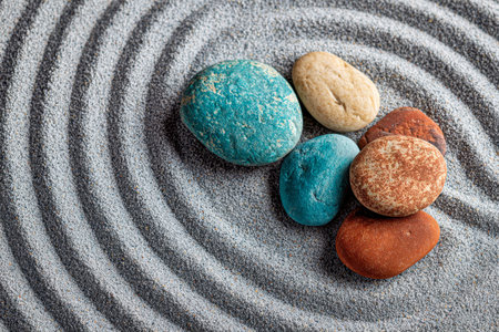 A serene display of vibrant stones thoughtfully positioned amidst meticulously swept sand patterns,...