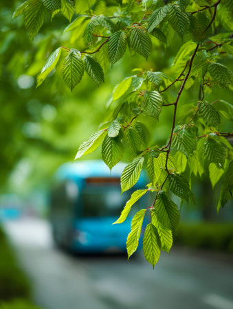 Bright, detailed foliage contrasts with a softly blurred city bus and greenery, capturing a peaceful moment on a tranquil urban street amid nature's vibrant tones.の写真素材