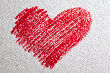 A lively crimson heart created with expressive colored pencil strokes on rough white paper, conveying warmth, passion, and heartfelt emotion through artistic charm.の写真素材