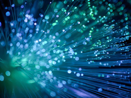 Vibrant blue and green threads of light radiate dynamically, casting a luminous glow with shimmering bokeh circles expanding into a deep, dark backdrop.の写真素材