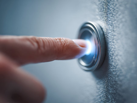 A hand presses a glowing, streamlined metal switch on a rough-textured backdrop, conveying innovation and the initiation of advanced digital functions.の写真素材