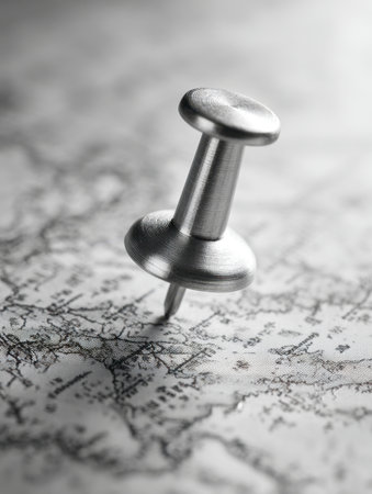 A close-up of a metal pushpin piercing a textured map, highlighting precision and focus in marking important destinations for travel and strategic planning.の写真素材