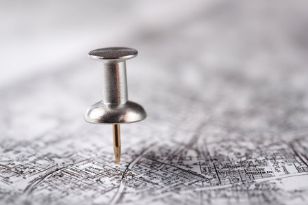 A sleek silver pin secures a spot on an intricate urban map, highlighting travel intentions amid a softly blurred backdrop that emphasizes the planning process.の写真素材