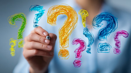 A creative individual sketches vibrant, overlapping question symbols of diverse scales on a clear backdrop, illustrating inquiry, innovation, and strategic thinking.の写真素材