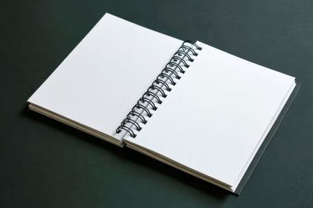 A sleek, open spiral notebook with pristine white pages rests on a dark background, inviting...