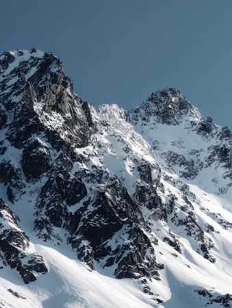 Towering snow-capped summits rise against a vivid azure sky, revealing intricate rocky patterns in a tranquil winter scene that embodies untouched natural beauty.の写真素材