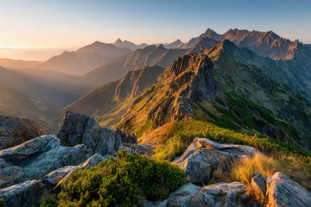 Amidst the warm glow of golden hour, jagged mountain summits cast shadows over lush greenery and rocky slopes, creating a breathtaking natural masterpiece.の写真素材