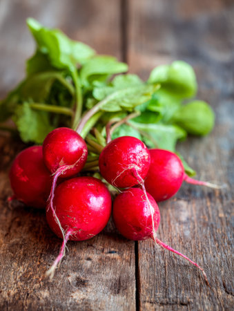 A colorful display of freshly harvested radishes with lush green foliage, placed on weathered wooden planks, embodying natural freshness and farm-to-eat quality.の写真素材