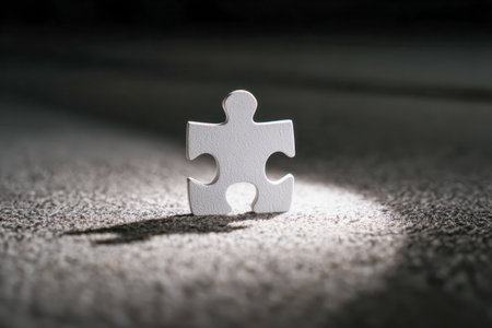 A solitary white puzzle fragment rests on a rough surface, highlighted by a piercing beam of light, embodying themes of uniqueness, clarity, and overcoming challengeの写真素材