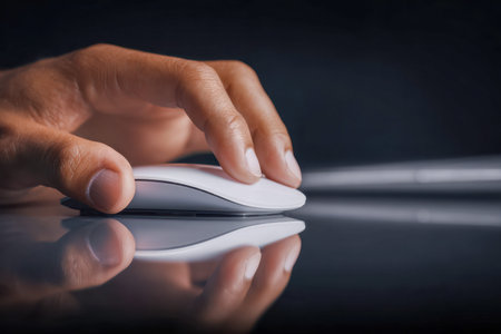 A sleek hand navigates a cordless mouse, mirrored on a polished surface under soft lighting,...