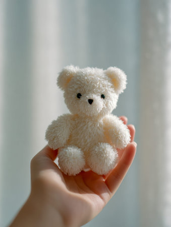 A tender grasp cradles a tiny plush toy amid a gentle backdrop, evoking feelings of innocence,...