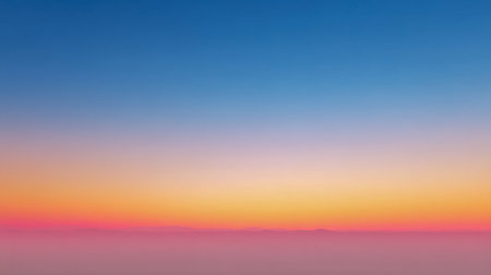 A peaceful horizon awakens as vivid color transitions stretch across the sky, with soft mist lying beneath, capturing a calming moment at dawn or dusk.の写真素材