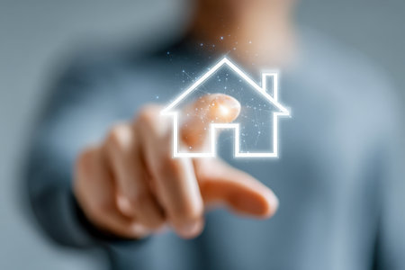 A person gestures towards an illuminated home symbol, representing advanced automation and digital property innovation amid a softly blurred background.の写真素材