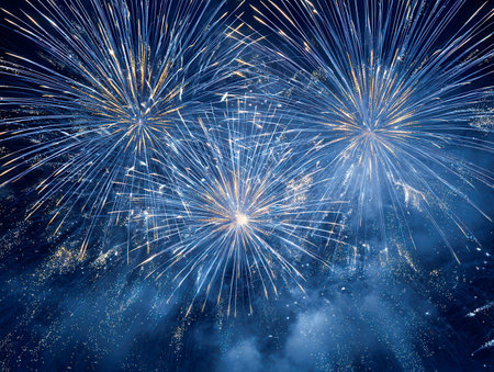A dazzling display of electric blue and shimmering gold bursts lights up the dark sky, leaving sparkling trails and glowing clouds that evoke joy and celebration.の写真素材