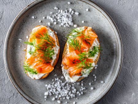 Elegant bruschetta bites featuring creamy cheese, fragrant dill, and silky smoked salmon, artfully arranged on a ceramic dish with glistening sea salt accents.の写真素材