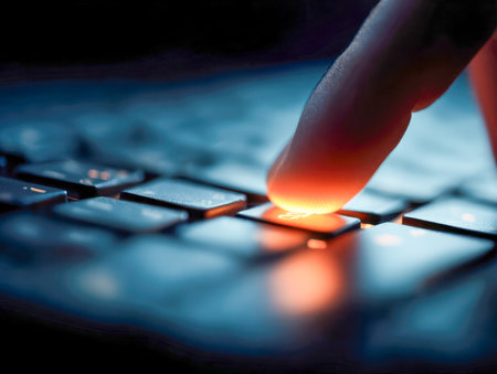 A finger presses a vibrant orange-lit key on a dark keyboard, evoking themes of innovation, digital control, and the power of technological interaction.の写真素材