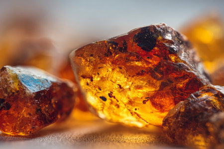 Warm amber hues emit a gentle glow, revealing their smooth, transparent surface and natural inclusions against a soft, textured backdrop.の写真素材