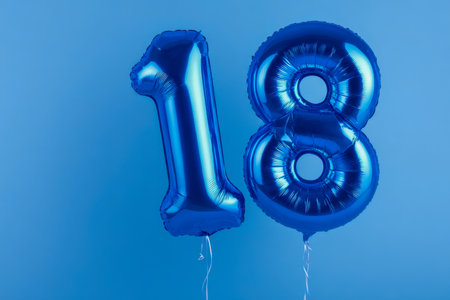 Shimmering metallic blue numeral balloons soar gracefully against a lively blue background, epitomizing festivity and achievement with sophistication and flair.の写真素材