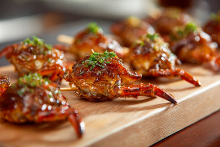 Juicy crab claws coated in a rich, glossy sauce, topped with vibrant herbs, and artfully arranged on a rustic wooden platter for a gourmet seafood experience.の写真素材