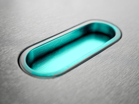 A minimalist, contemporary pull embedded into a surface, featuring a vibrant turquoise accent that contrasts beautifully with its smooth, matte brushed steel finish.の写真素材