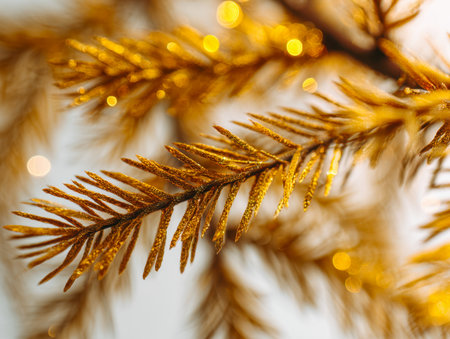 Close-up of shimmering golden pine branches illuminated by soft, glowing lights, evoking a cozy, joyful holiday ambiance with a dreamy, blurred backdrop.の写真素材