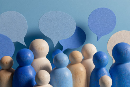 Colorful wooden figures in calming blue and neutral beige engage through speech bubbles, illustrating themes of teamwork, dialogue, and ideas sharing on a vibrant blの写真素材