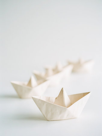 A series of delicate paper vessels aligned on a clean white background, their arrangement evoking minimalism and gentle shadows through natural light.の写真素材