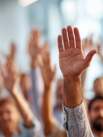 A lively assembly of individuals from various backgrounds enthusiastically participate by lifting their hands in a vibrant, well-lit indoor environment, showcasing cの写真素材