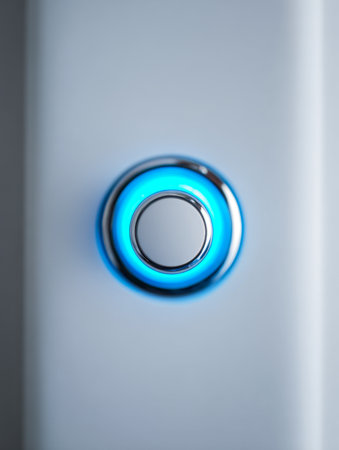 A polished metal control button featuring a luminous blue ring, set against a clean, contemporary backdrop that emphasizes cutting-edge interface and tech aestheticsの写真素材