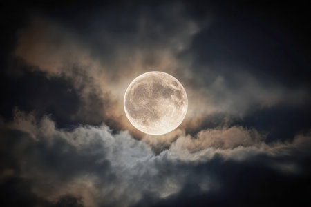 A luminous full moon illuminates a moody sky, casting a gentle halo through delicate wisps and shadows, creating a captivating contrast in the nocturnal atmosphere.の写真素材