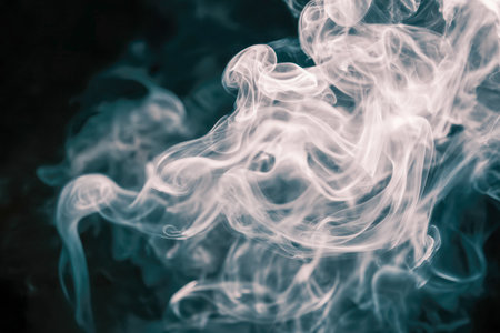 Delicate tendrils of luminous white vapor dance gracefully across a shadowy backdrop, forming an intriguing and hypnotic abstract design full of mystery.の写真素材