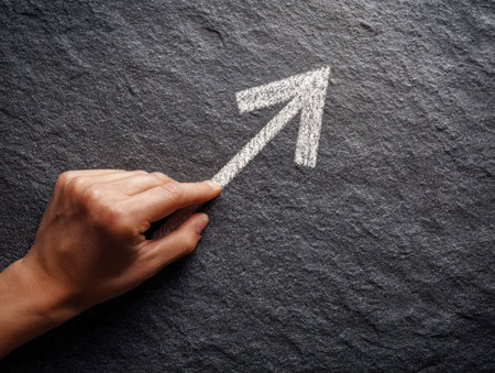 A skilled hand sketches a rising arrow over a rugged dark background, embodying ambition, forward momentum, and the pursuit of success in personal or entrepreneurialの写真素材