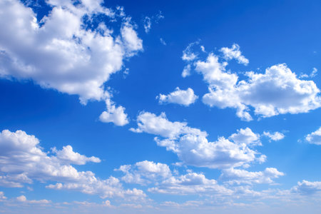 A serene sky painted in vibrant blue, dotted with gentle, billowy clouds that evoke tranquility and...
