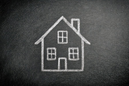 A minimalist chalk sketch of a cozy residence with inviting windows and a chimney, set against a textured blackboard that evokes imagination and the idea of sanctuarの写真素材