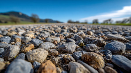 A close-up of rough gravel stepping stones winding through countryside greenery, inviting viewers to explore a peaceful, sunlit trail beneath a vivid blue sky.の写真素材