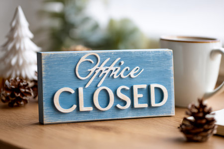 A charming, weathered blue sign with white text announcing closure, nestled among pinecones, a cozy cup, and festive ornaments on a wooden tabletop.の素材