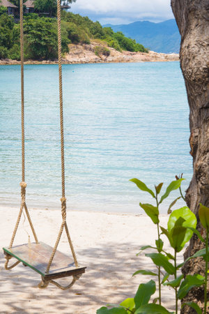 Isolated empty sandy beach with empty wooden swing at Thongson Bay in the morning