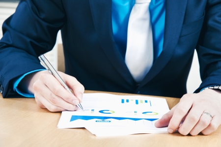 Business man making notes to sales reportの写真素材