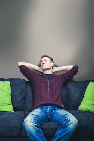 Man sitting on sofa relaxing and dreamingの写真素材