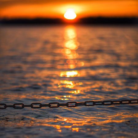 Sunset and old, rusty chainの写真素材