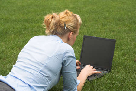 Blonde business woman laying on the grass with laptop. の写真素材