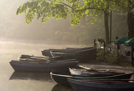 Boats at a waterside cafe in a sunny misty morningの写真素材
