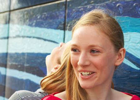 outdoor portrait of two laughing girls next to a painted wallの写真素材