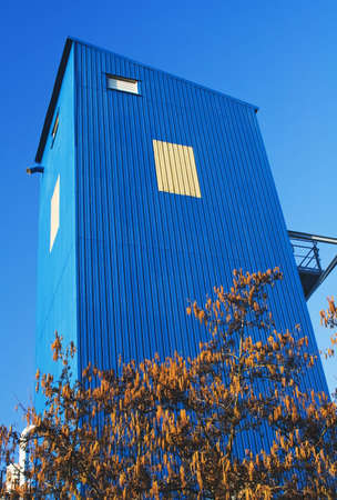 Bright blue industrial building against a clear blue skyの写真素材