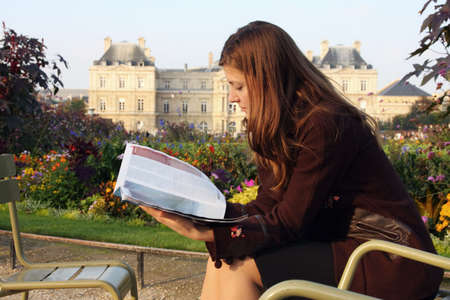 Pretty girl reading magazine in Luxembourg garden (Paris). Late afternoon sun. Autumn colors.の写真素材