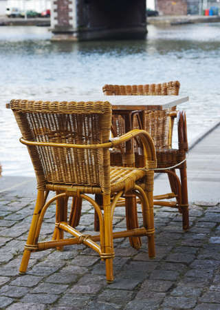 wicker chairs of an open-air cafe installed on cobllestone pavement の写真素材