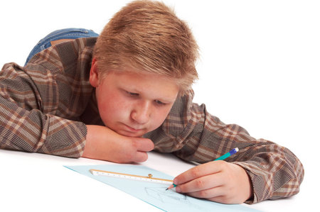 Blond boy drawing a pencil picture lying on the floor; isolated on white