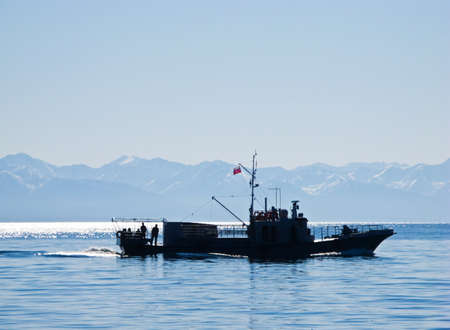 Silhouette of a motorboat driving along the mountains (lake Baikal, Russia)の写真素材