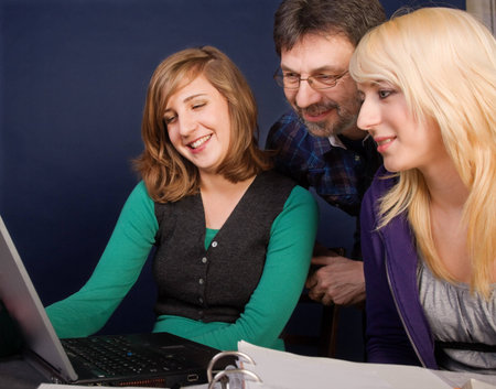 Smiling teenager girls and their father looking at laptop screen